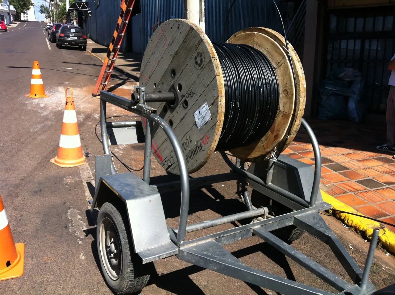 Bobina de cabo de fibra óptica em um reboque na rua, sinalizada com cones, no lançamento da fibra em 2012