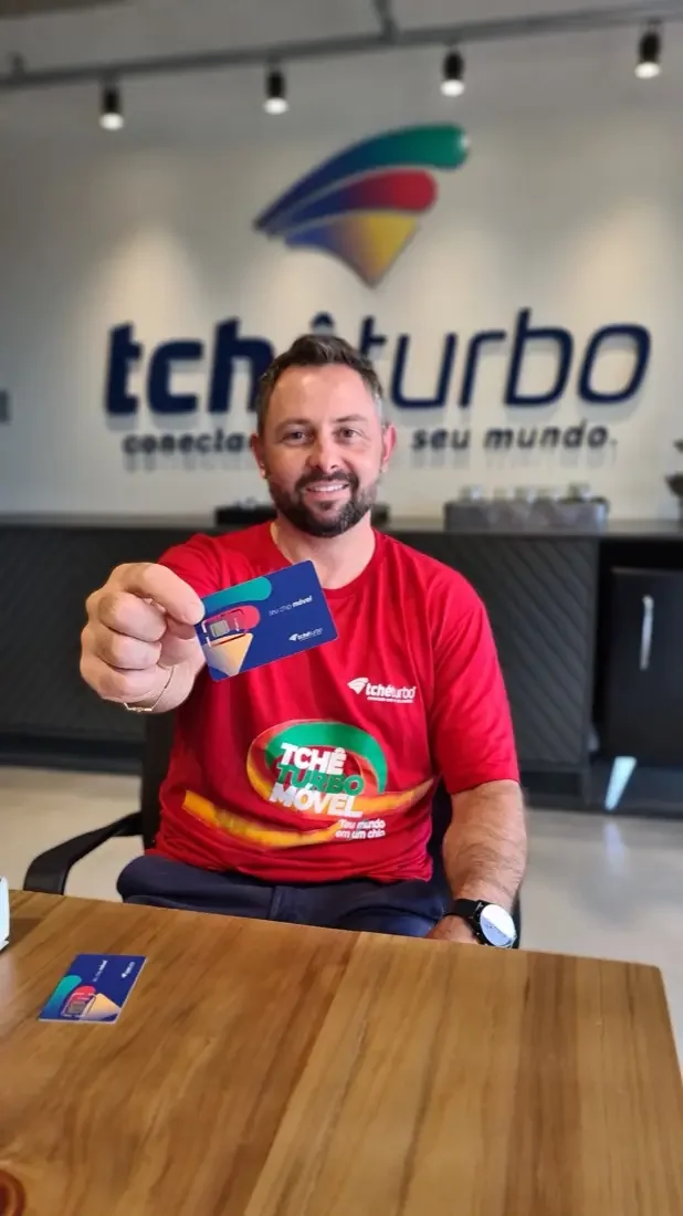 Colaborador com a camiseta do Tchê Móvel mostrando o primeiro chip de telefonia móvel da Tchêturbo, em 2021